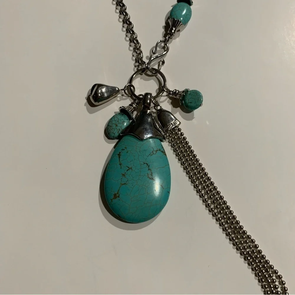 Silver tone and turquoise necklace with oversized pendant and charms.